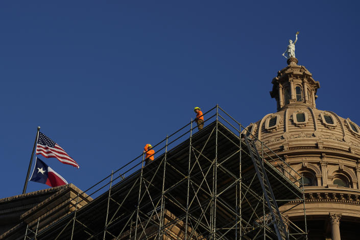 Construction workers look out from scaffolding for a roof restoration project as the Texas Capitol as the first day of the 88th Texas Legislative Session begins in Austin, Texas, Tuesday, Jan. 10, 2023. (AP Photo/Eric Gay)