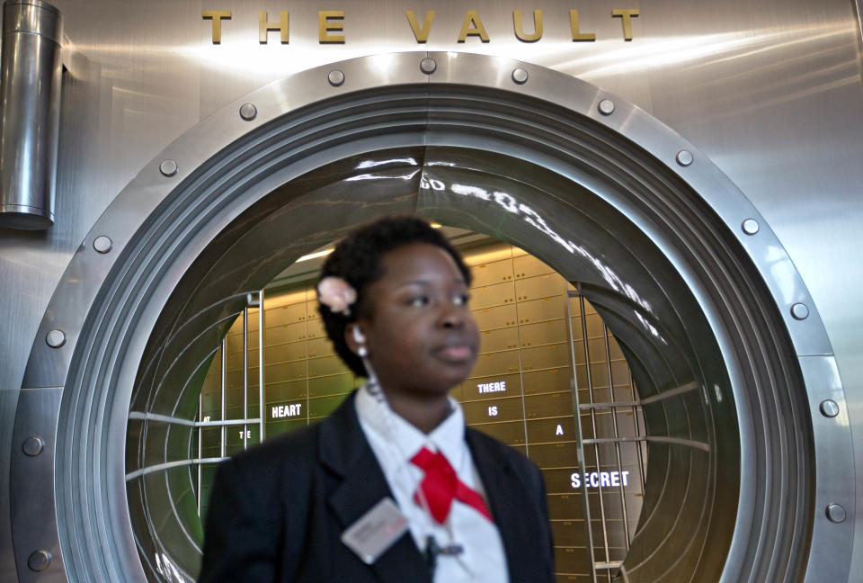 In this Friday, Aug. 9, 2013 photo, Marilyn Buamah, a secret formula security officer, stands outside the vault containing the “secret recipe” for Coca-Cola while waiting for a tour group at the World of Coca-Cola museum, in Atlanta. The 127-year-old recipe for Coke sits inside an imposing steel vault that’s bathed in red security lights, while security cameras monitor the area to make sure the fizzy formula stays a secret. (AP Photo/David Goldman)