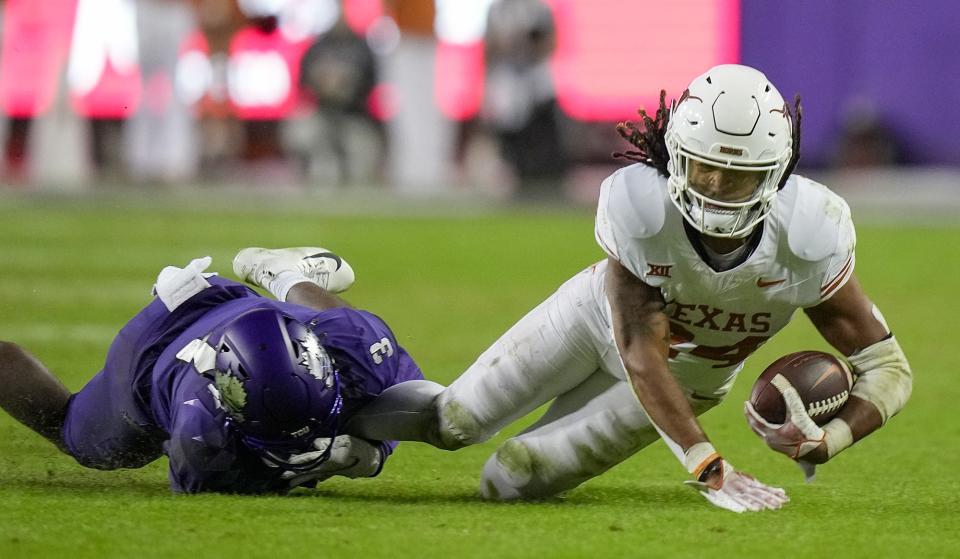 Texas Longhorns running back Jonathon Brooks (24) is pulled down by TCU Horned Frogs safety Mark Perry (3) late in the fourth quarter of Saturday's 29-26 win in Fort Worth. Brooks sustained a season-ending knee injury on the play.
