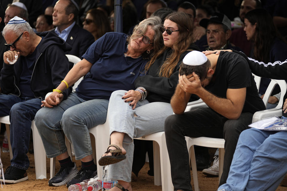 Dikla Shamriz, center left, holds the hand of her husband Avi, left, as they mourn with other relatives during the funeral of their 26-year-old son Alon in the cemetery of Kibbutz Shefayim, Israel, Sunday Dec. 17, 2023. Shamriz was one of three hostages mistakenly shot to death by Israeli troops Friday in a battle-torn neighborhood of Gaza City.(AP Photo/Ohad Zwigenberg)