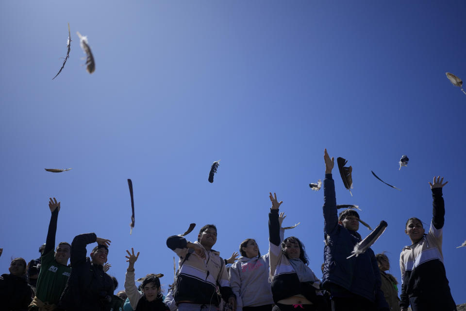 Youths throw Andean Condor feathers into the air symbolizing their good wishes for two newly liberated Andean condors who were born in captivity almost three years prior at the Andean Condor Conservation Program in Sierra Paileman in the Rio Negro province of Argentina, Friday, Oct. 14, 2022. For 30 years the program has hatched chicks in captivity, rehabilitated others and freed them across South America. (AP Photo/Natacha Pisarenko)