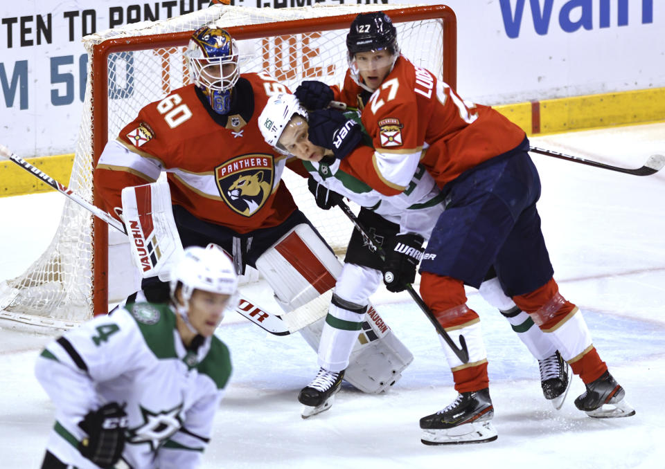 Dallas Stars left wing Joel Kiviranta (25) gets pushed by Florida Panthers center Eetu Luostarinen (27) as goaltender Chris Driedger (60) looks on during the first period of an NHL hockey game Wednesday, Feb. 24, 2021, in Sunrise, Fla. (AP Photo/Jim Rassol)