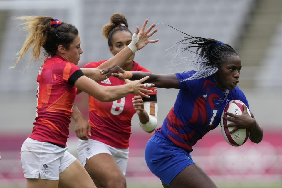 France's Seraphine Okemba runs with the ball, pursued by Britain's Abbie Brown, left, and Celia Quansah, obscured, in their women's rugby sevens semifinal match at the 2020 Summer Olympics, Saturday, July 31, 2021 in Tokyo, Japan. (AP Photo/Shuji Kajiyama)