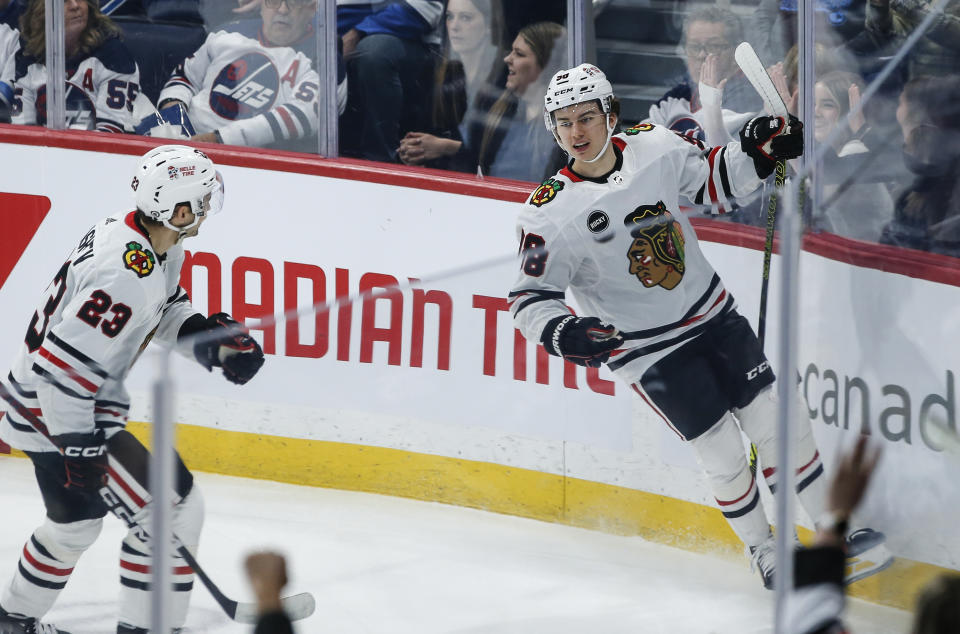 Chicago Blackhawks' Connor Bedard (98) and Philipp Kurashev (23) celebrate Bedard's goal against the Winnipeg Jets during the first period of an NHL game in Winnipeg, Manitoba, Saturday, Dec. 2, 2023. (John Woods/The Canadian Press via AP)