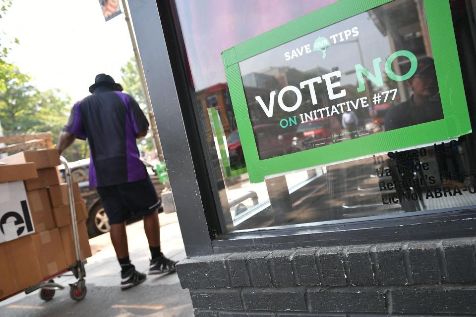 Initiative #77 was a 2018 ballot measure to gradually raise the minimum wage that tipped workers receive; passed by Washington, D.C. voters, the City Council repealed it. <a href="https://www.gettyimages.com/detail/news-photo/man-walks-by-a-vote-no-on-initiative-poster-on-june-18-2018-news-photo/977876412?adppopup=true" rel="nofollow noopener" target="_blank" data-ylk="slk:Mandel Ngan/AFP via Getty Images;elm:context_link;itc:0;sec:content-canvas" class="link ">Mandel Ngan/AFP via Getty Images</a>