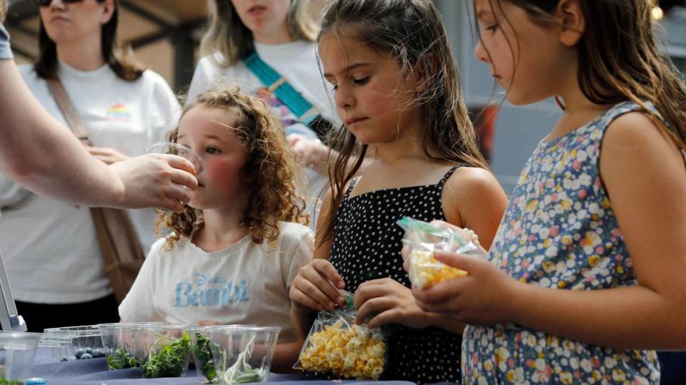 From left, Harvest Nolan, 6, Opal Quick, 6, and Rosie Quick, 7, smell herbs at the Power of Produce table at the Lexington Farmers Market on Saturday, June 24, 2023 at Fifth Third Pavilion in Lexington, Ky.