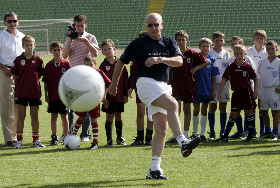 FILE - Former British soccer player, Sir Bobby Charlton, shows young Sarajevo FC players how to shoot and score from an 11 meter line at Sarajevo Olympic stadium, Aug 10, 2005. Bobby Charlton, an English soccer icon who survived a plane crash that decimated a Manchester United team destined for greatness to become the heartbeat of his country's 1966 World Cup-winning team, has died. He was 86. A statement from Charlton's family, released by United, said he died Saturday Oct. 21, 2023 surrounded by his family. (AP Photo/Hidajet Delic, File)