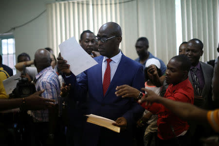 Haiti's Minister of Planning and External Cooperation Aviol Fleurant delivers copies of the statement about the resolution on the Oxfam scandal to the journalists after a news conference in Port-au-Prince, Haiti, June 13, 2018. REUTERS/Andres Martinez Casares