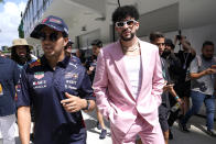 Red Bull driver Sergio Perez, of Mexico, left, walks in the paddock with Puerto Rican reggaeton musician Bad Bunny, right, before a Formula One Miami Grand Prix auto race at Miami International Autodrome, Sunday, May 8, 2022, in Miami Gardens, Fla. (AP Photo/Lynne Sladky)