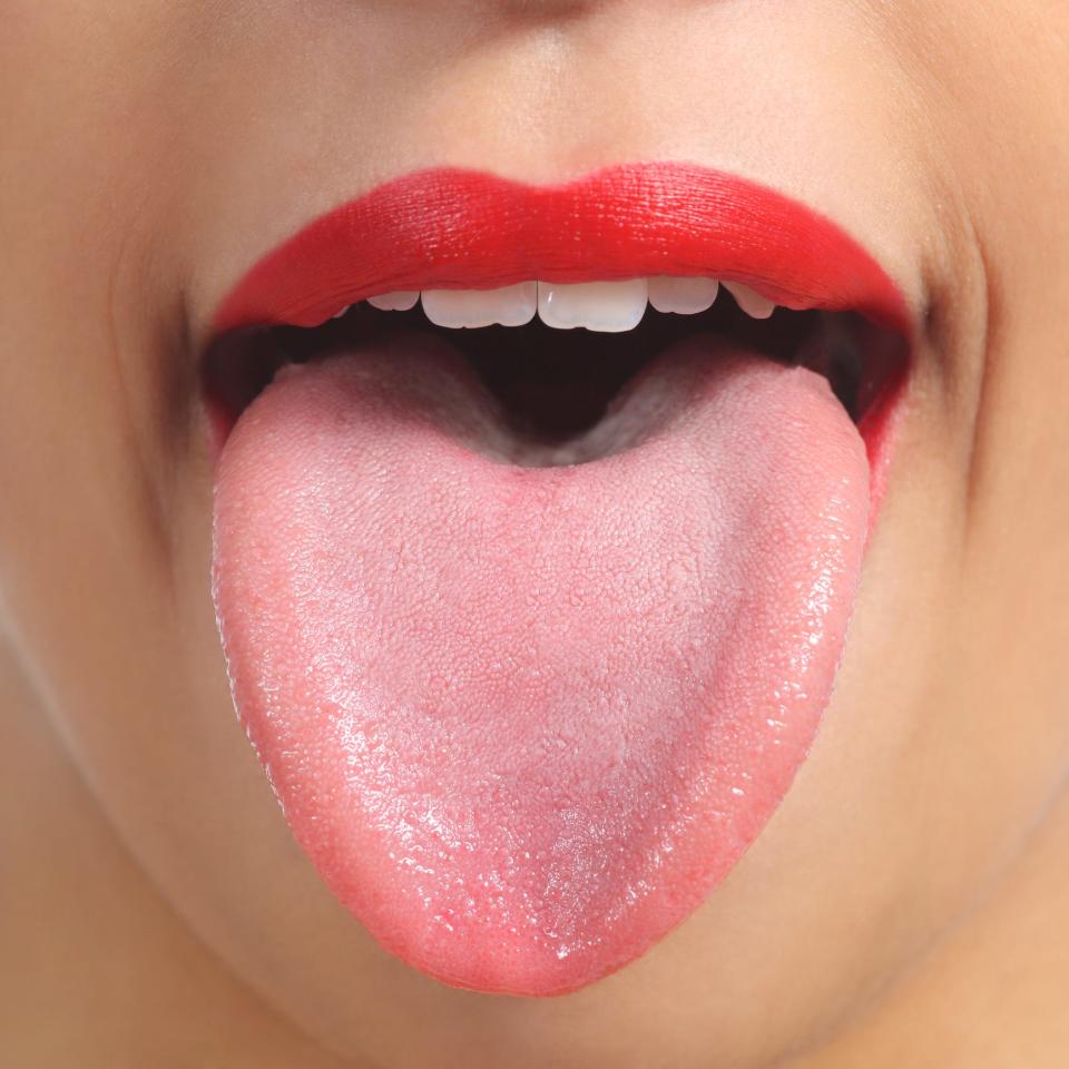 Close up view of a woman with red lipstick sticking her tongue out.