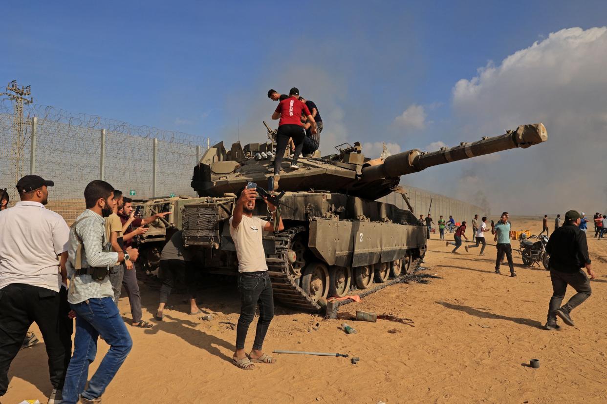 Palestinians take control of an Israeli tank after crossing the border fence with Israel from Khan Yunis in the southern Gaza Strip on October 7, 2023. Barrages of rockets were fired at Israel from the Gaza Strip at dawn as militants from the blockaded Palestinian enclave infiltrated Israel, with at least on