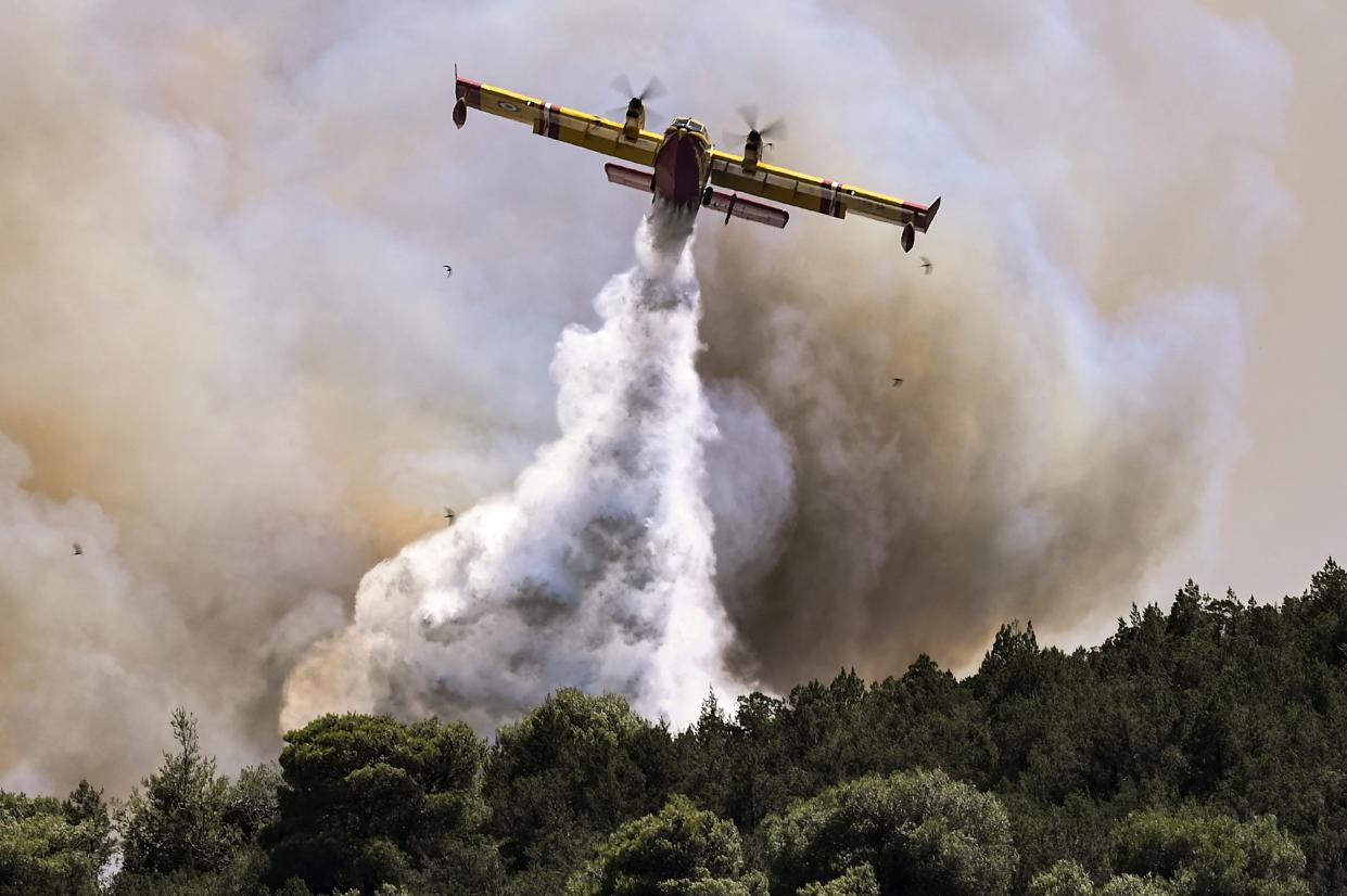 A Canadair firefighting plane sprays water during a fire in Dervenochoria, north-west of Athens (AFP via Getty Images)
