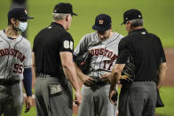 Houston Astros starting pitcher Jake Odorizzi has his belt inspected by first base umpire Ted Barrett (65) and home plate umpire Angel Hernandez, right, during the first inning of a baseball game against the Baltimore Orioles, Monday, June 21, 2021, in Baltimore. (AP Photo/Julio Cortez)