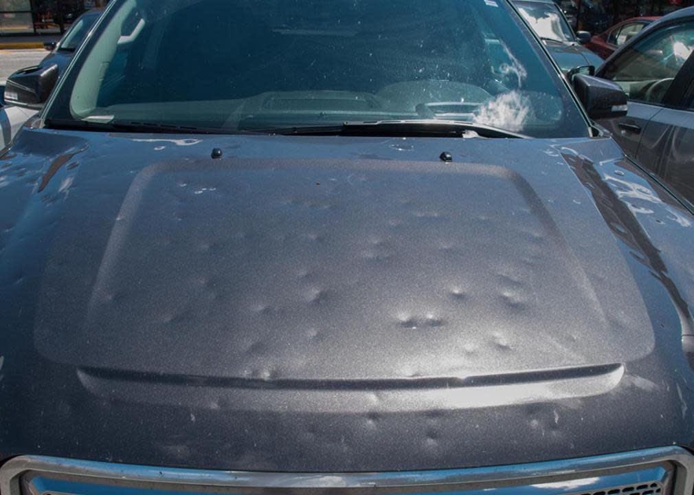 Black car with dents after a hail storm