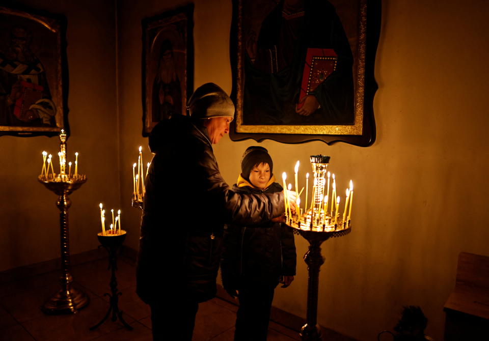 A woman lights a candle during an Orthodox Palm Sunday mass in Bucha.