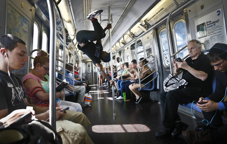 FILE - In this June 17, 2014 file photo, Dashawn Martin, center, a member with the dance troupe W.A.F.F.L.E., which stands for We Are Family For Life Entertainment, performs on a subway, in New York. Subway acrobats, dancers and musicians on Tuesday, Aug 12, 2014 decried what they said was heavy-handed policing, gathering outside City Hall to join critics of a police clampdown on minor offenses. Transit rules generally allow performing for tips in parts of subway stations, but not in trains or with amplifiers, unless artists have permits. More than 240 subway performers have been arrested so far this year, about four times as many as during the same period last year, according to police statistics. (AP Photo/Bebeto Matthews, File)