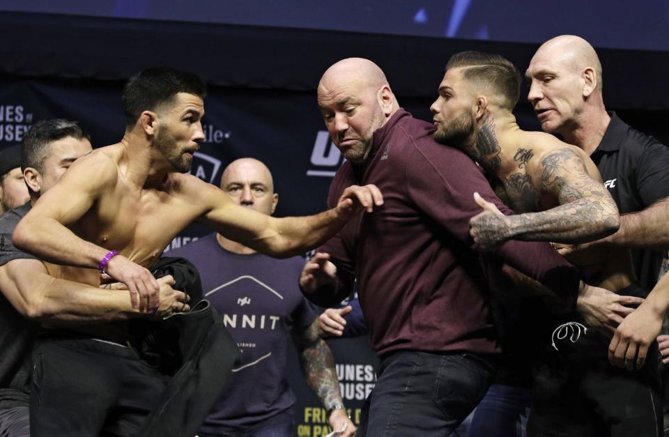 UFC president Dana White, center, gets between Dominick Cruz, left, and Cody Garbrandt during an event for UFC 207, Thursday, Dec. 29, 2016, in Las Vegas. The two are scheduled to fight in a mixed martial arts bantamweight championship bout Saturday in Las Vegas. (AP Photo/John Locher)