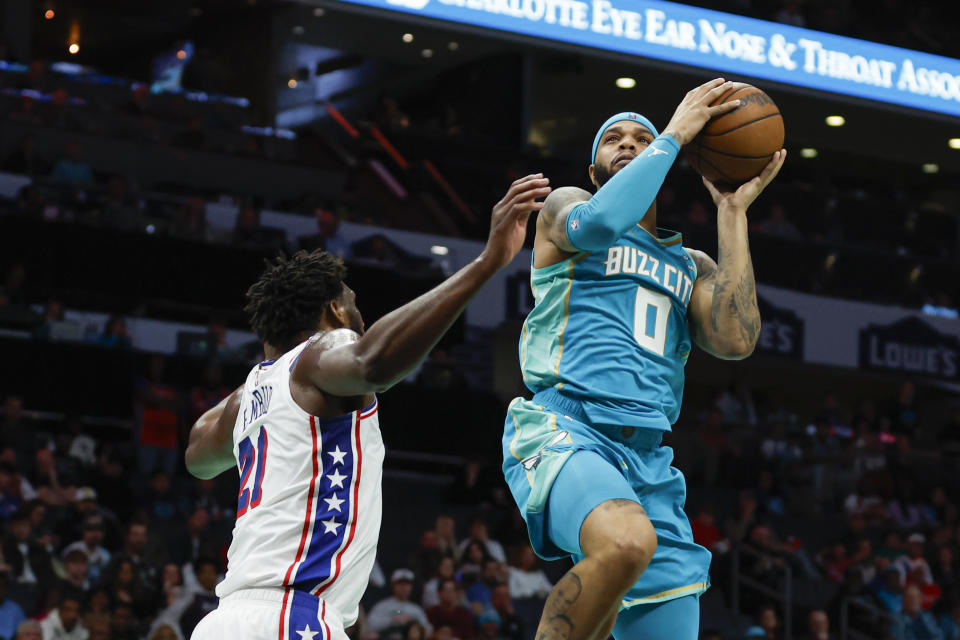 Charlotte Hornets forward Miles Bridges (0) drives to the basket against Philadelphia 76ers center Joel Embiid (21) during the first half of an NBA basketball game in Charlotte, N.C., Saturday, Dec. 16, 2023. (AP Photo/Nell Redmond)