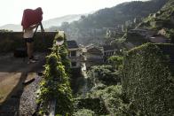 A photographer uses a large format camera to take pictures as tourists visit the abandoned fishing village of Houtouwan on the island of Shengshan July 26, 2015. (REUTERS/Damir Sagolj)