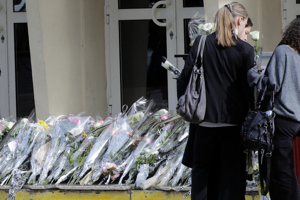 Flowers lay at the entrance of the Gambetta high school, Monday, Oct. 16, 2023 in Arras, northern France. French authorities say the high school where a teacher was fatally stabbed in an attack last week has been evacuated over a bomb alert, as France's President cut short travel plans abroad to host a security meeting Monday. (AP Photo/Michel Spingler)