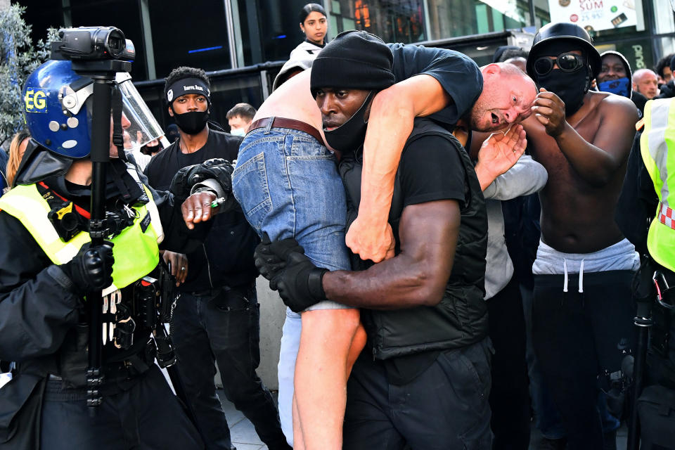 Image: Patrick Hutchinson, a protester, carries a suspected far-right counter-protester who was injured, to safety, near Waterloo station during a Black Lives Matter protest (Dylan Martinez / Reuters)