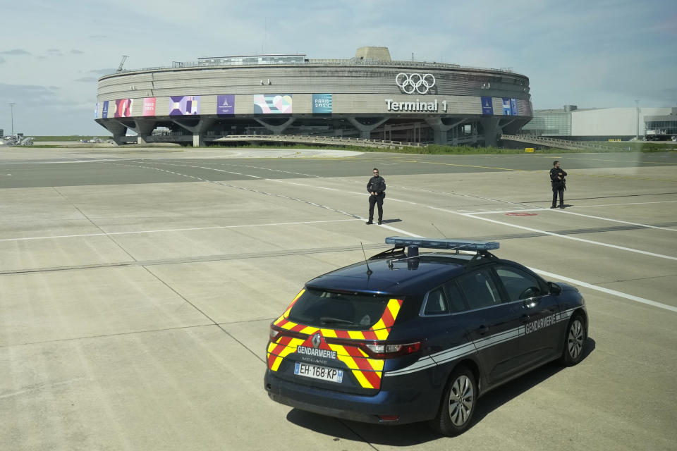 Gendarmes pose in front of the Charles de Gaulle airport, terminal 1, where the olympic rings were installed, in Roissy-en-France, north of Paris, Tuesday, April 23, 2024 in Paris. (AP Photo/Thibault Camus)