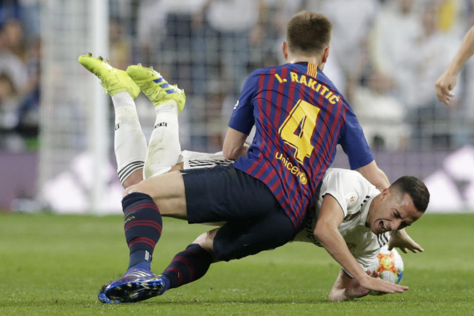 Real forward Lucas Vazquez, background, is tackled by Barcelona midfielder Ivan Rakitic during the Copa del Rey semifinal second leg soccer match between Real Madrid and FC Barcelona at the Bernabeu stadium in Madrid, Spain, Wednesday Feb. 27, 2019. (AP Photo/Andrea Comas)