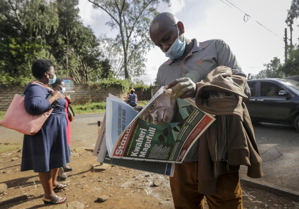 A man reads a copy of the Daily Nation morning newspaper reporting the death of neighboring Tanzania's President John Magufuli on a street in Nairobi, Kenya Thursday, March 18, 2021. Magufuli, a prominent COVID-19 skeptic whose populist rule often cast his country in a harsh international spotlight, died Wednesday aged 61 of heart failure, it was announced by Vice President Samia Suluhu. Headline in Swahili reads "Goodbye Magufuli." (AP Photo/Khalil Senosi)