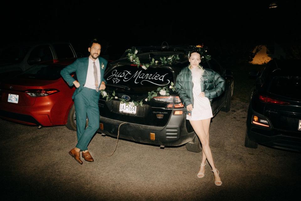 a man and woman walking next to a car at night