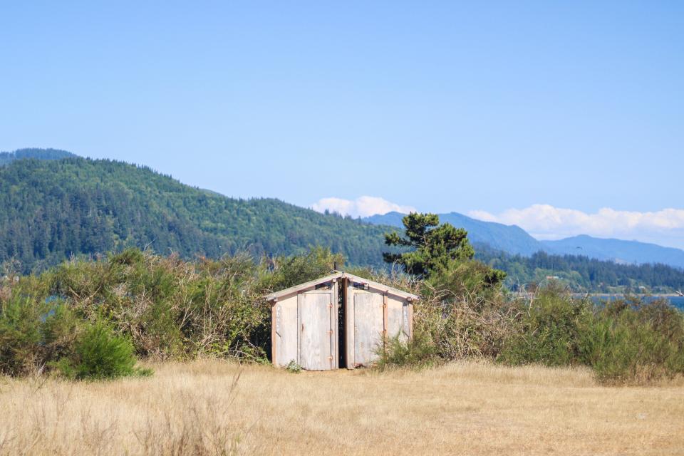 An outhouse sits between vegetation off of Tillamook Bay July 28, 2023.