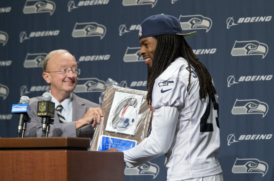 FILE - Seattle Seahawks' Richard Sherman accepts Pro Football Writers of America (PFWA) 2015 Good Guy Award from ESPN's John Clayton at the Seahawk's NFL football team headquarters in Renton, Wash., on Wednesday, Sept. 23, 2015. Clayton died Friday, March 18, 2022, following a short illness. He was 67. (AP Photo/John Froschauer, File)