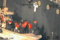 This image released by the U.S. Department of Defense on Monday, June 17, 2019, and taken from a U.S. Navy helicopter, shows what the Navy says are members of the Islamic Revolutionary Guard Corps Navy removing an unexploded limpet mine from the M/T Kokuka Courageous. (U.S. Department of Defense via AP)