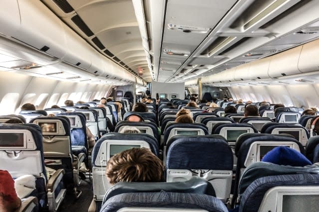 Passengers in a plane seen from behind above seats