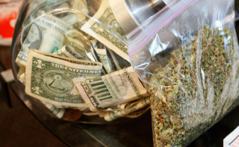 A bag of marijuana being prepared for sale sits next to a money jar at BotanaCare in Northglenn, Colorado, on December 31, 2013.