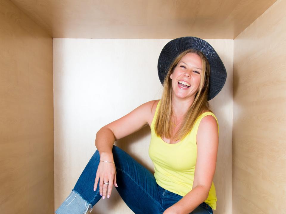 Woman smiling in yellow tanktop and black hat