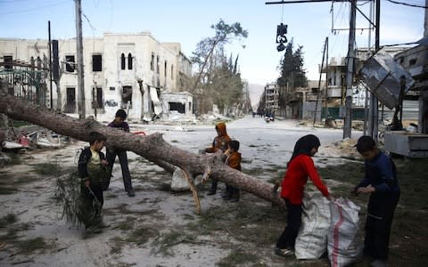 Children gather wood in the besieged town of Douma, Eastern Ghouta, in Damascus - Credit: Reuters