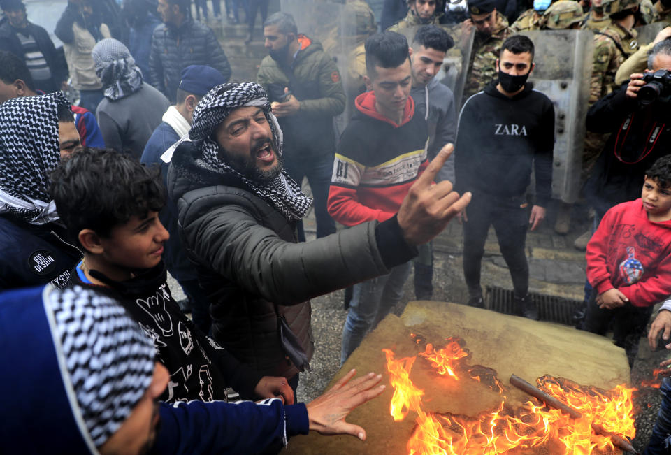 A protester shouts slogans in front the house of a Lebanese lawmaker, during a protest against deteriorating living conditions and strict coronavirus lockdown measures, in Tripoli, north Lebanon, Thursday, Jan. 28, 2021. Violent confrontations overnight between protesters and security forces in northern Lebanon left a 30-year-old man dead and more than 220 people injured, the state news agency said Thursday. (AP Photo/Hussein Malla)