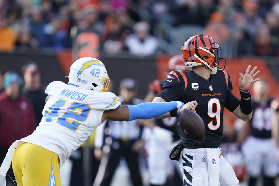 Cincinnati Bengals quarterback Joe Burrow (9) fumbles as he is hit by Los Angeles Chargers' Uchenna Nwosu (42) during the first half of an NFL football game, Sunday, Dec. 5, 2021, in Cincinnati. (AP Photo/Michael Conroy)