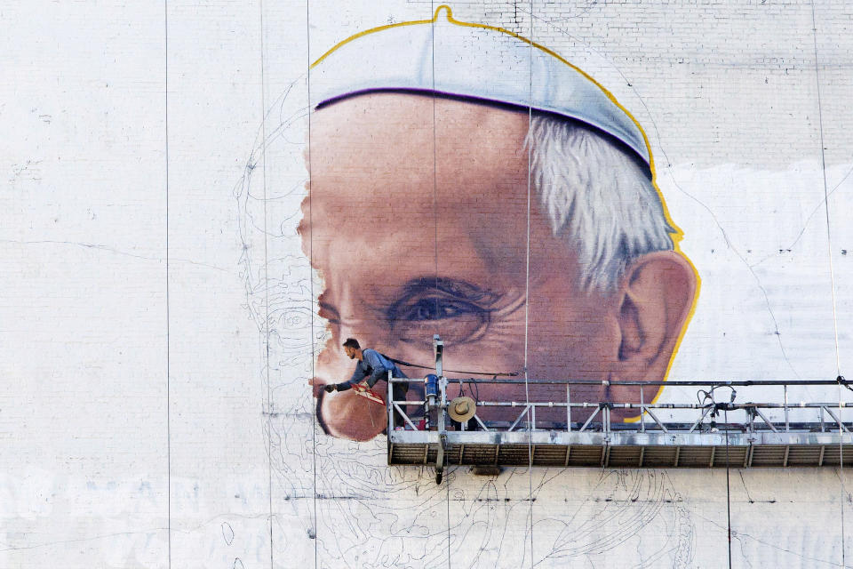 FILE - A painter outlines the Pope's nose on the side of a building in New York on Thursday, Aug. 27, 2015, a month before the visit of Pope Francis. (AP Photo/Mark Lennihan, File)