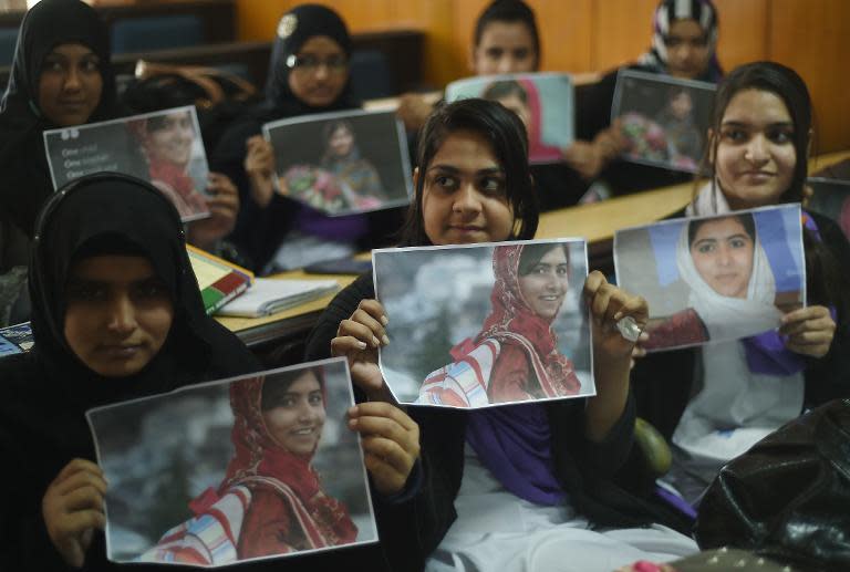 Pakistani students pose for a photograph holding posters bearing the image of Nobel Peace Prize winner Malala Yousafzai at a ceremony in Islamabad on December 10, 2014