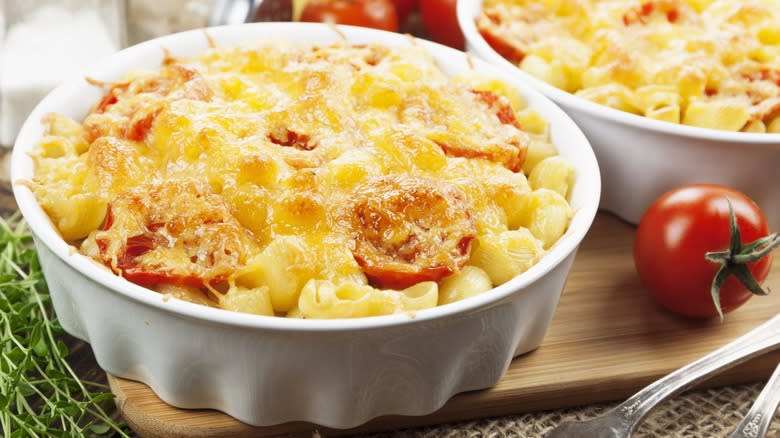 Baked macaroni and cheese in two ramekins with slices of tomatoes