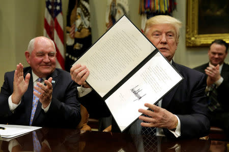 U.S. President Donald Trump shows a signed executive order next to Secretary of Agriculture Sonny Perdue during a roundtable discussion with farmers at the White House in Washington, U.S. April 25, 2017. REUTERS/Yuri Gripas