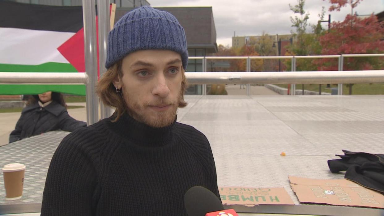 Hani Alaf, 24, says Humber College ordered him to leave campus last Thursday after the Syrian-Canadian post-graduate student put up about a dozen stickers around the Lakeshore campus in Toronto with the Palestinian flag on them and the words 'Boycott Israeli Apartheid.'   (Michael Charles Cole/CBC - image credit)