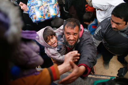 A displaced Iraqi with his son prepares to get on a truck to be carried to a safe place, as Iraqi forces battle with Islamic State militants, in western Mosul, Iraq March 8, 2017. REUTERS/Suhaib Salem TPX IMAGES OF THE DAY