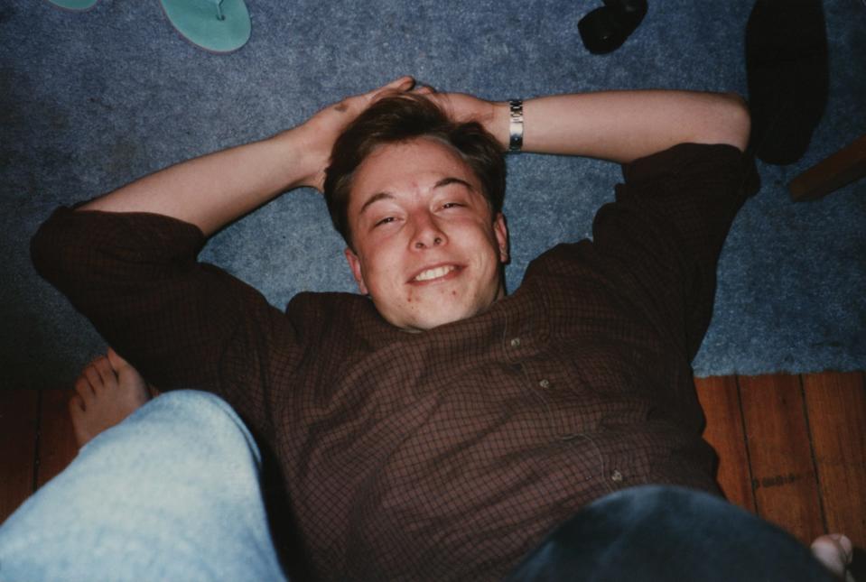 Elon Musk goofing about upside down on the floor, with Jennifer Gwynne above him.