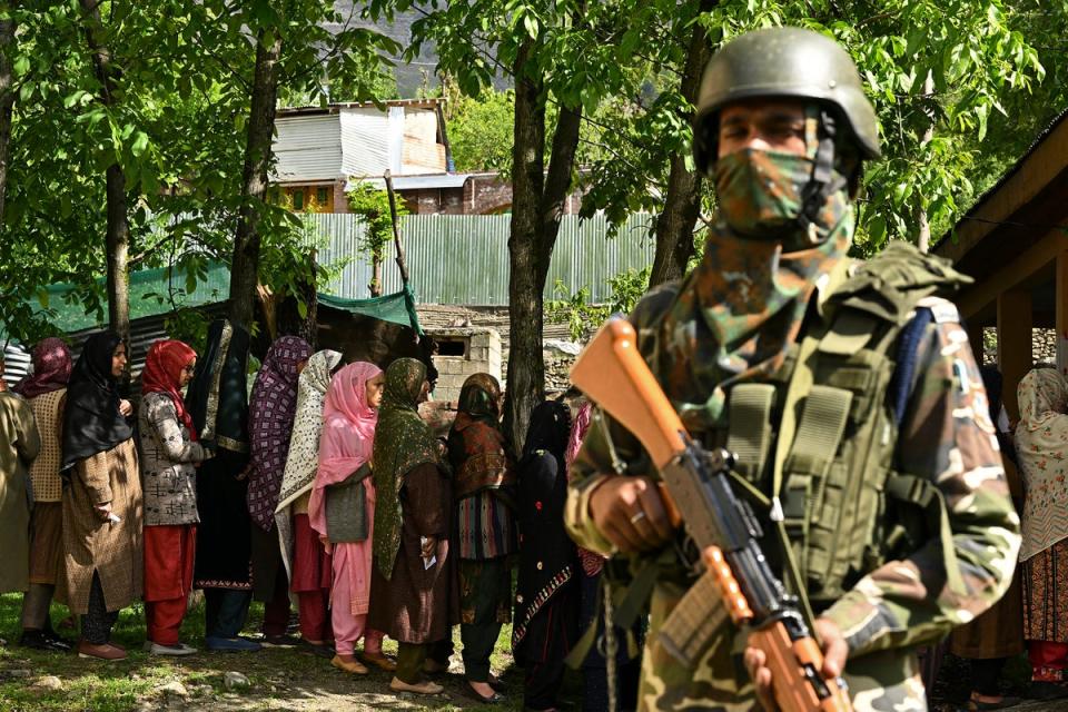 An Indian security personnel stands guard as voters queue up to cast their ballots at a polling station in Ganderbal district, northeast of Srinagar (AFP via Getty Images)