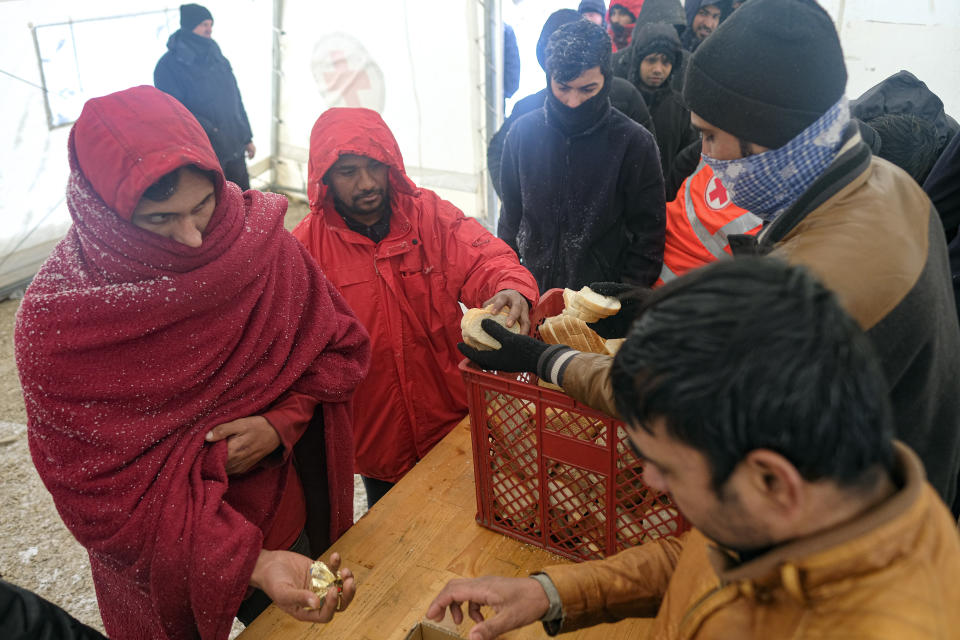 Migrants wait in a line to get food and warm beverages, at the Lipa camp, outside Bihac, Bosnia, Monday, Jan. 11, 2021. Aid workers say migrants staying at a camp in northwestern Bosnia have complained or respiratory and skin diseases after spending days in make-shift tents and containers amid freezing weather and snow blizzards. Most of the hundreds of migrants at the Lipa facility near Bosnia's border with Croatia on Monday have been accommodated in heated military tents following days of uncertainty after a fire gutted most of the camp on Dec. 23. (AP Photo/Kemal Softic)