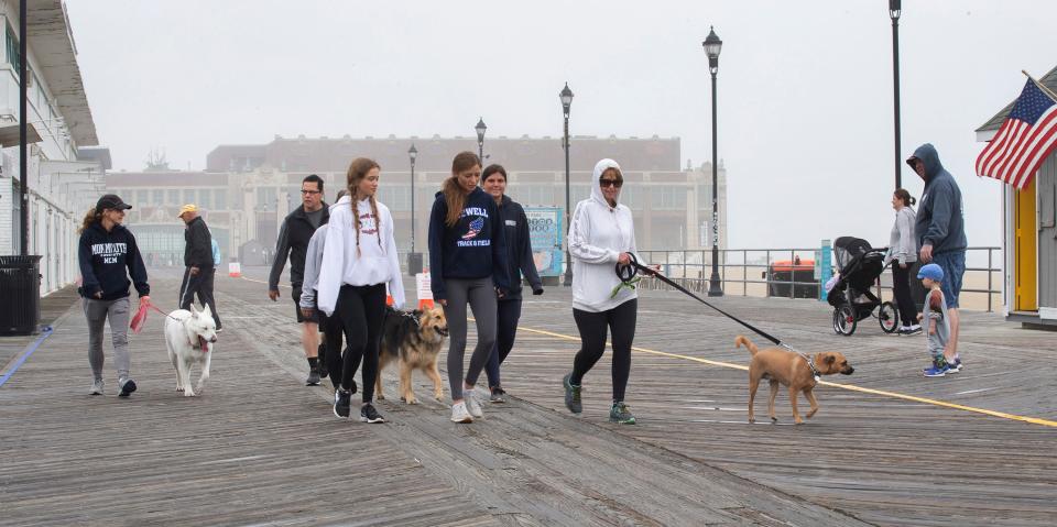 A group of friends walk their dogs along the Asbury Park boardwalk.