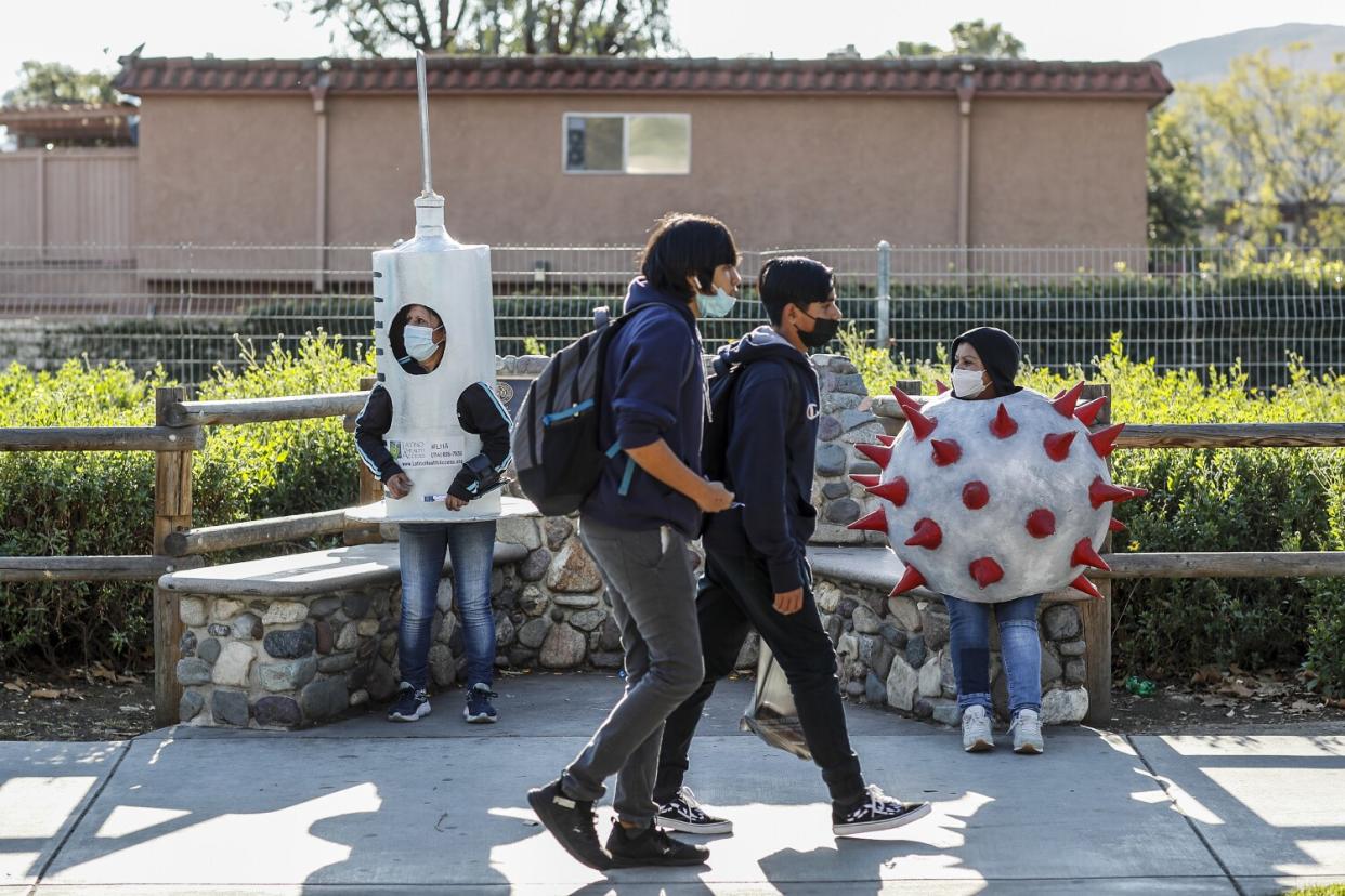 Socorro Juarez, left, dressed up as a vaccine syringe and Rosa Cardona, right, dressed as the coronavirus