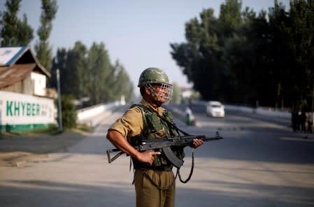 An Indian security personnel stands guard on a deserted road during restrictions after scrapping of the special constitutional status for Kashmir by the Indian government, in Srinagar